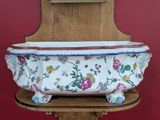 a large white bowl with flowers on it on a wooden stand