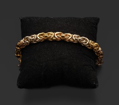 un bracelet en chaîne d'or posé sur un coussin noir