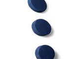 trois comprimés bleus sont disposés les uns au-dessus des autres sur une surface blanche