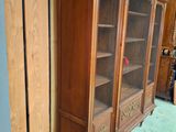 a tall wooden cabinet with glass doors in a room