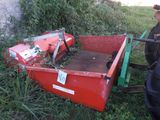 un tracteur rouge avec une remorque rouge dans l'herbe