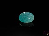 a close up of a green gemstone on a black surface