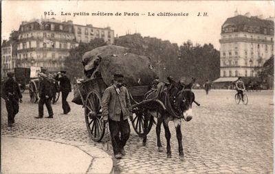un homme marchant dans la rue avec deux ânes tirant une charrette