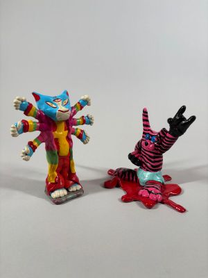 Deux figurines de clowns sont placées l'une à côté de l'autre sur une surface blanche