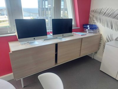 two computers on a desk in a room with a window