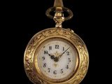 une montre de poche en or avec un cadran blanc sur fond noir