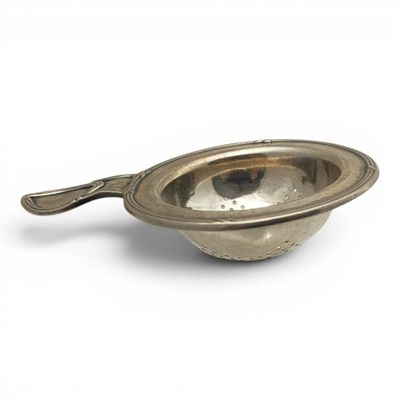 a silver bowl with a spoon in it on a white surface