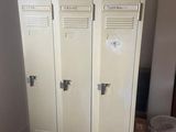 two lockers in the corner of a room next to a trash can