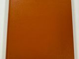 an orange book sitting on top of a table next to a white wall
