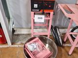 une machine rose posée par terre à côté d'une chaise rose