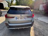 the rear end of a silver bmw suv parked in front of a barn