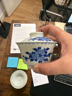 a person holding a blue and white tea pot on a desk