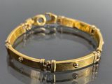 une image d'un bracelet en or sur une surface réfléchissante