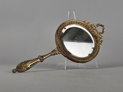 an image of a gold colored mirror with a handle on a clear stand