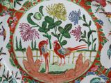 une assiette colorée ornée d'un oiseau et de fleurs