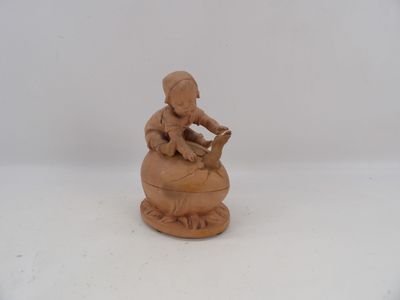 a small figurine of a woman sitting on top of a pot