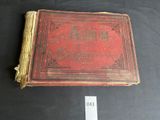an old book with a red cover sitting on top of a table