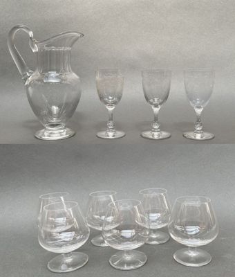 six wine glasses and a pitcher sitting on a table