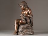 statue of a woman sitting on a rock holding a dog
