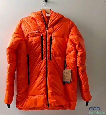 une doudoune orange accrochée au mur, avec une étiquette dessus