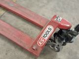 a red hand truck sitting on the floor in a warehouse