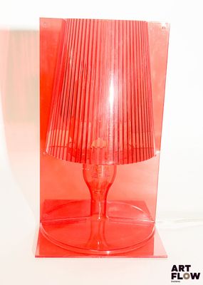 une lampe rouge posée sur une table transparente