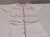 doll ' s white dress with red trim and buttons on a white table