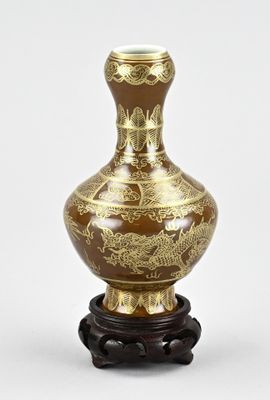 un vase marron orné de motifs dorés, posé sur un socle