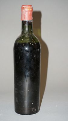une bouteille de vin posée sur une table, dont l'ombre se projette sur le mur