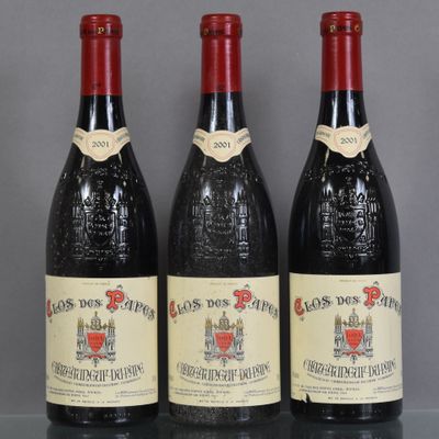 three bottles of red wine sit on a glass table