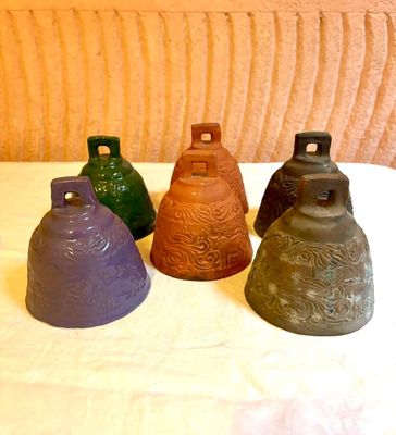 cinq clochettes de couleurs différentes posées sur une surface blanche