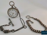 une montre de poche en argent avec une chaîne autour d'elle