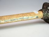 a rusty pipe with a wooden handle on a white surface