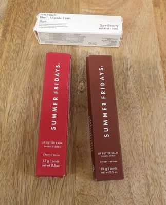 two boxes of lip butter sitting on top of a wooden table