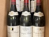 six bottles of wine are in a cardboard box on a table