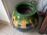 a large green vase sitting on the floor next to a wall