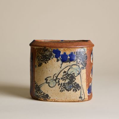 un récipient marron et bleu orné d'un motif floral