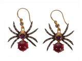 a pair of spider earrings with garnets on them