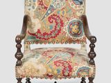 un fauteuil au revêtement richement orné, dont le dossier est recouvert d'un tissu à motifs floraux