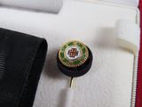 a small black object with a gold and green emblem on it