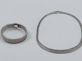 two pieces of silver jewelry on a white surface