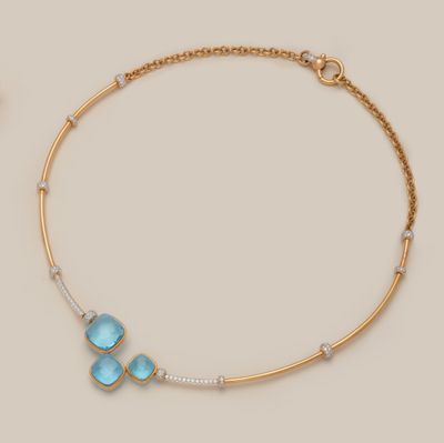 un collier en or orné de pierres bleues et de diamants sur fond beige