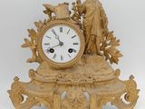 une horloge en or surmontée d'une statue