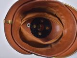 a close up of a brown leather hat with a black button