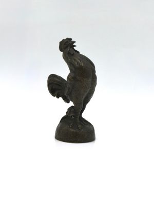 bronze figurine of a rooster on a rock on a white background