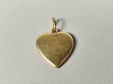 a gold heart charm on a white surface