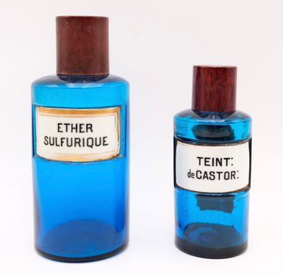 pair of blue glass bottles with wooden lids and labels on them
