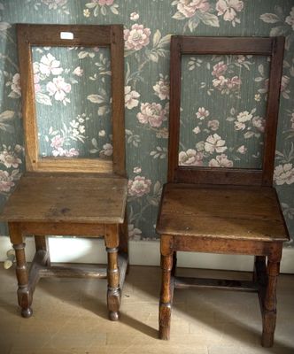 two wooden chairs sitting next to each other in a room