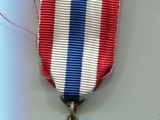 une médaille ornée d'un ruban rouge, blanc et bleu