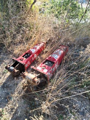 two cans of soda sitting on the ground next to a bush